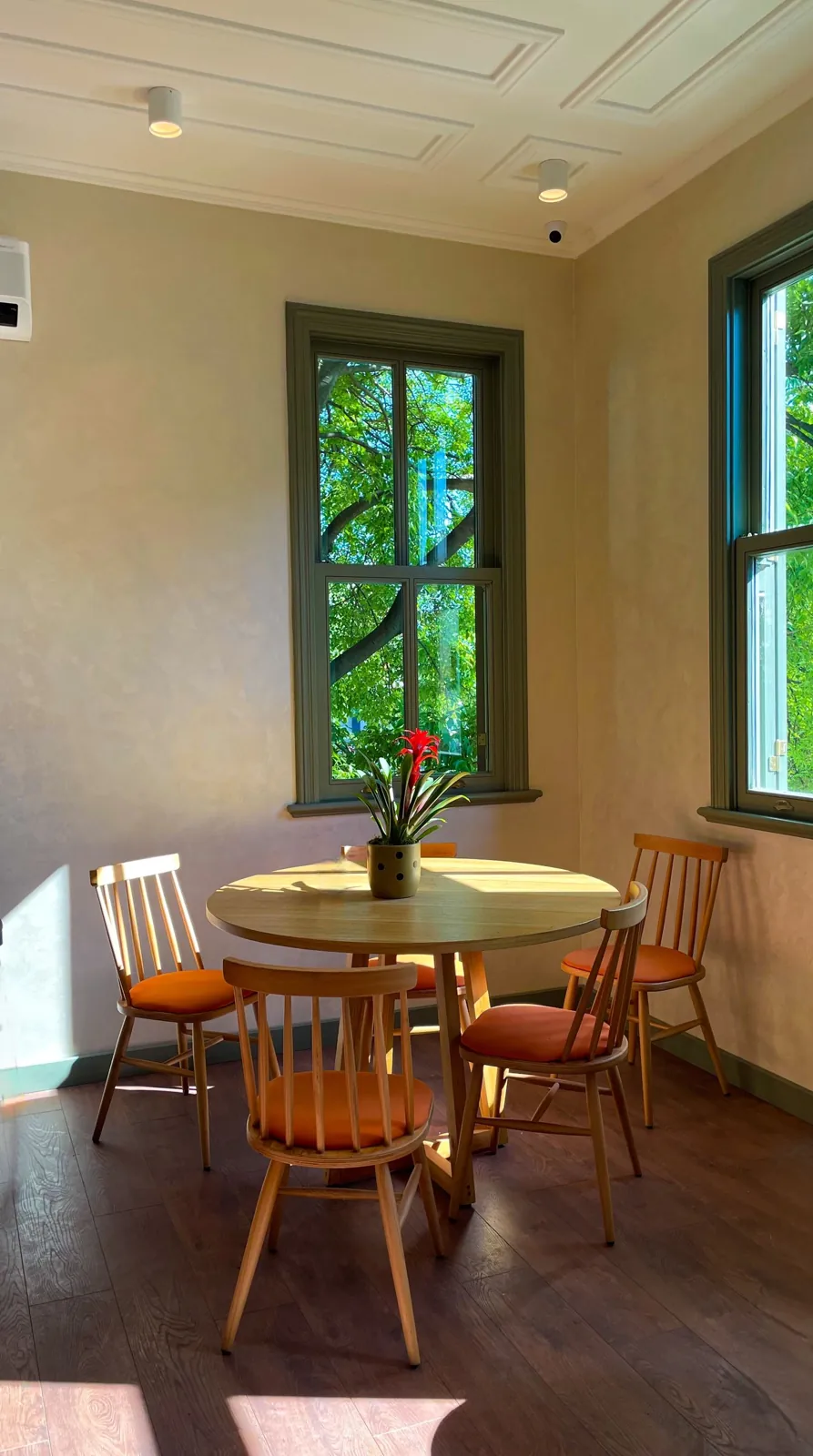 Round wooden dining table beside bright windows