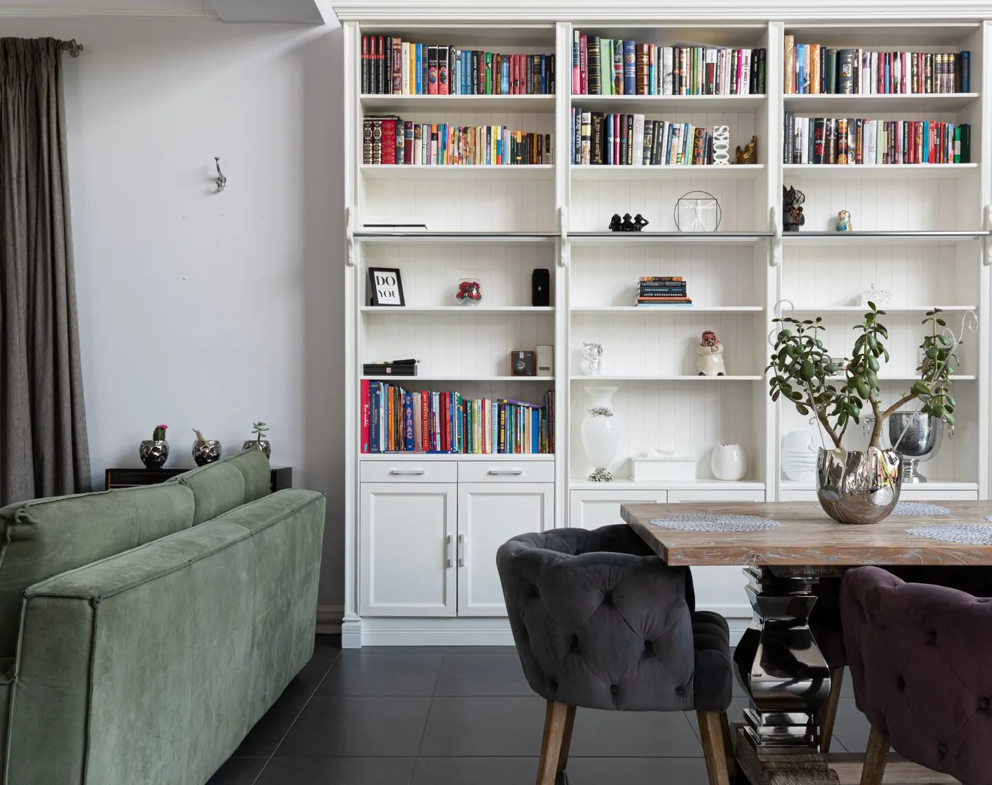 Living room with shelving, a green sofa and a separate chair
