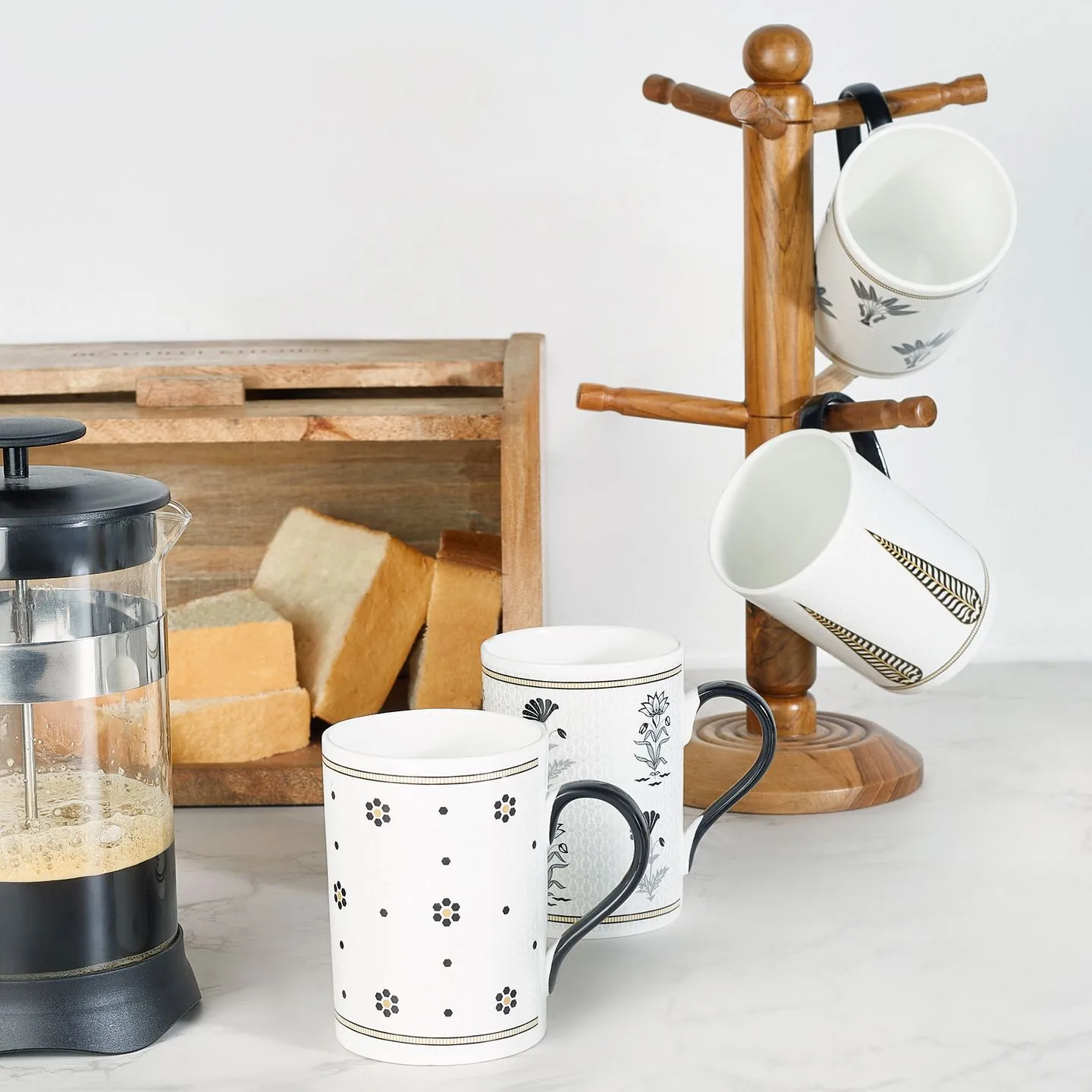 Mugs, bread and a French press on a kitchen worktop