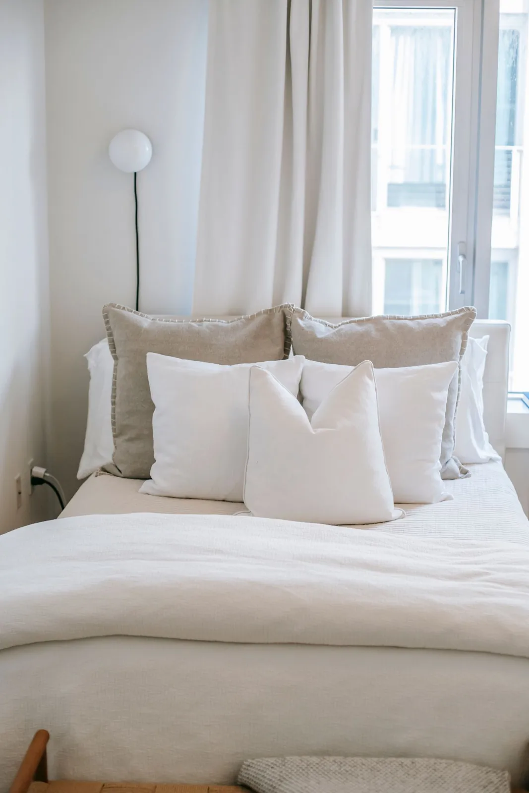 White bedding and cushions in a softly lit bedroom