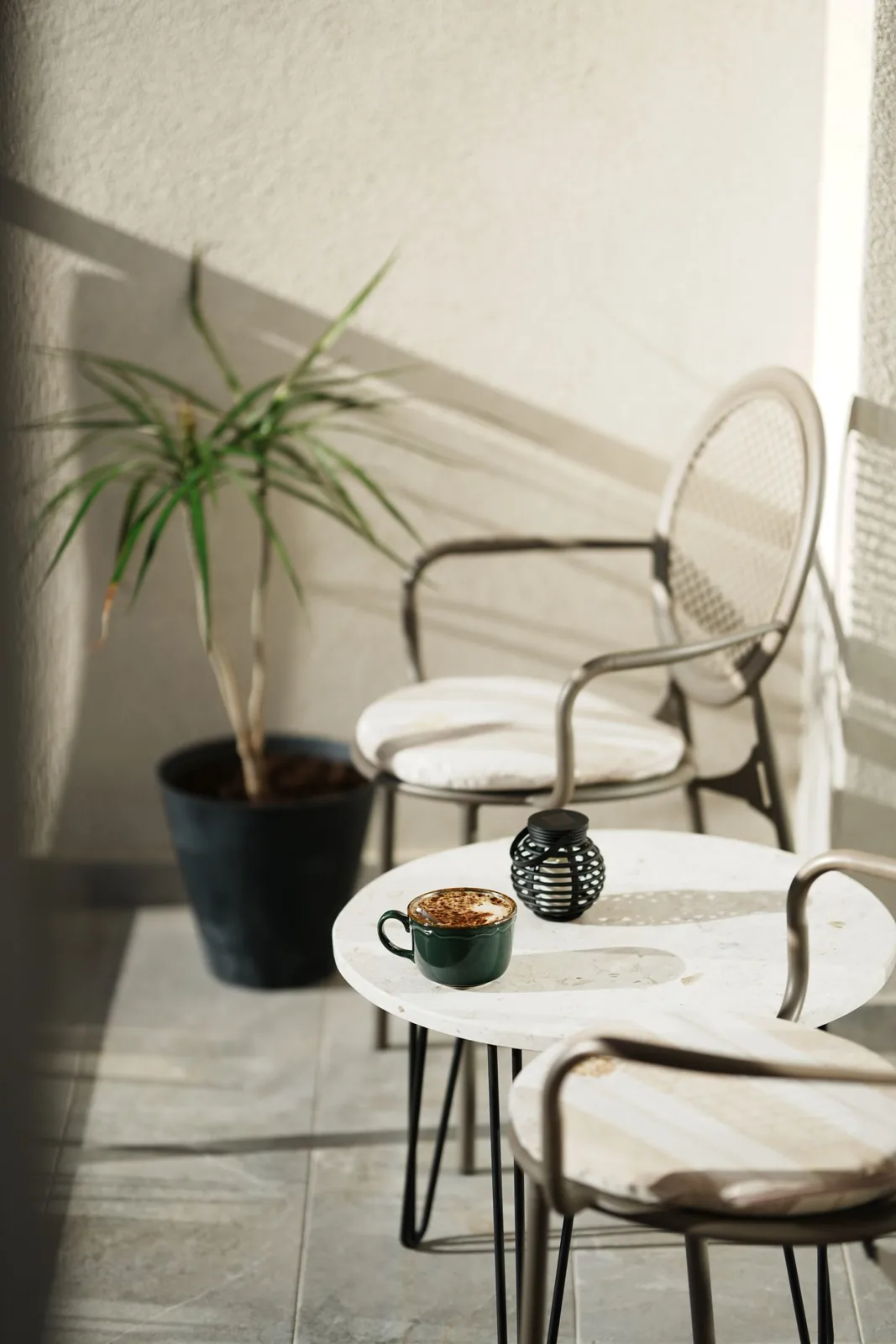 Coffee and a potted plant beside balcony seating