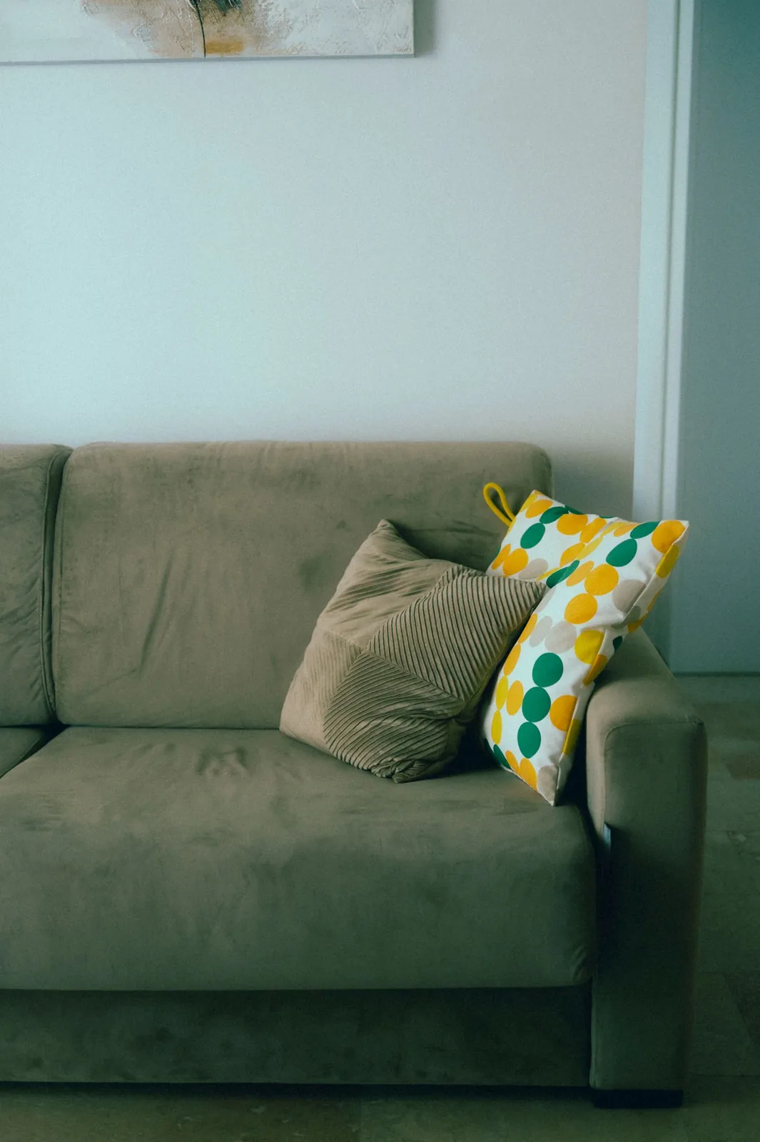 Green sofa with a bright patterned accent cushion