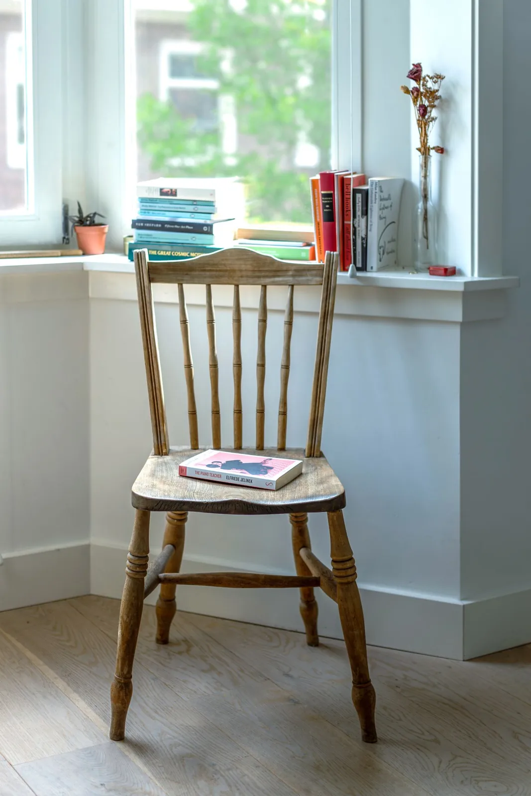 Wooden reading chair with a book beside a window