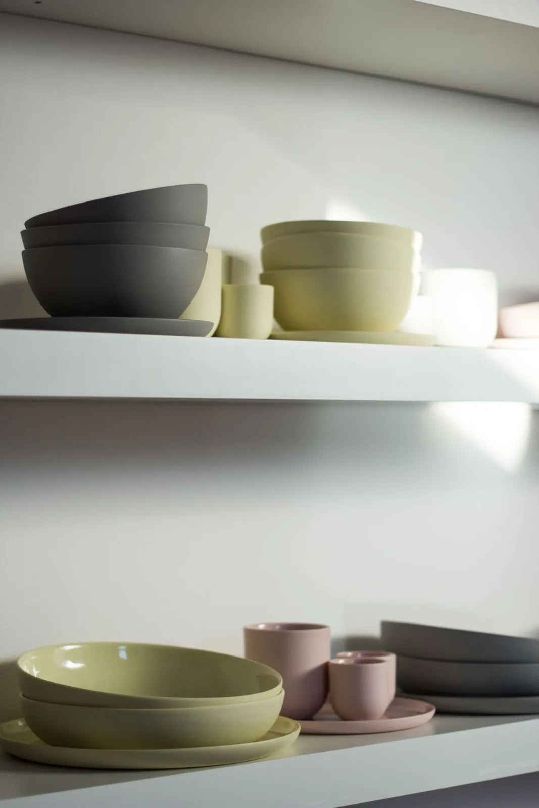 Pastel bowls and cups arranged on a kitchen shelf
