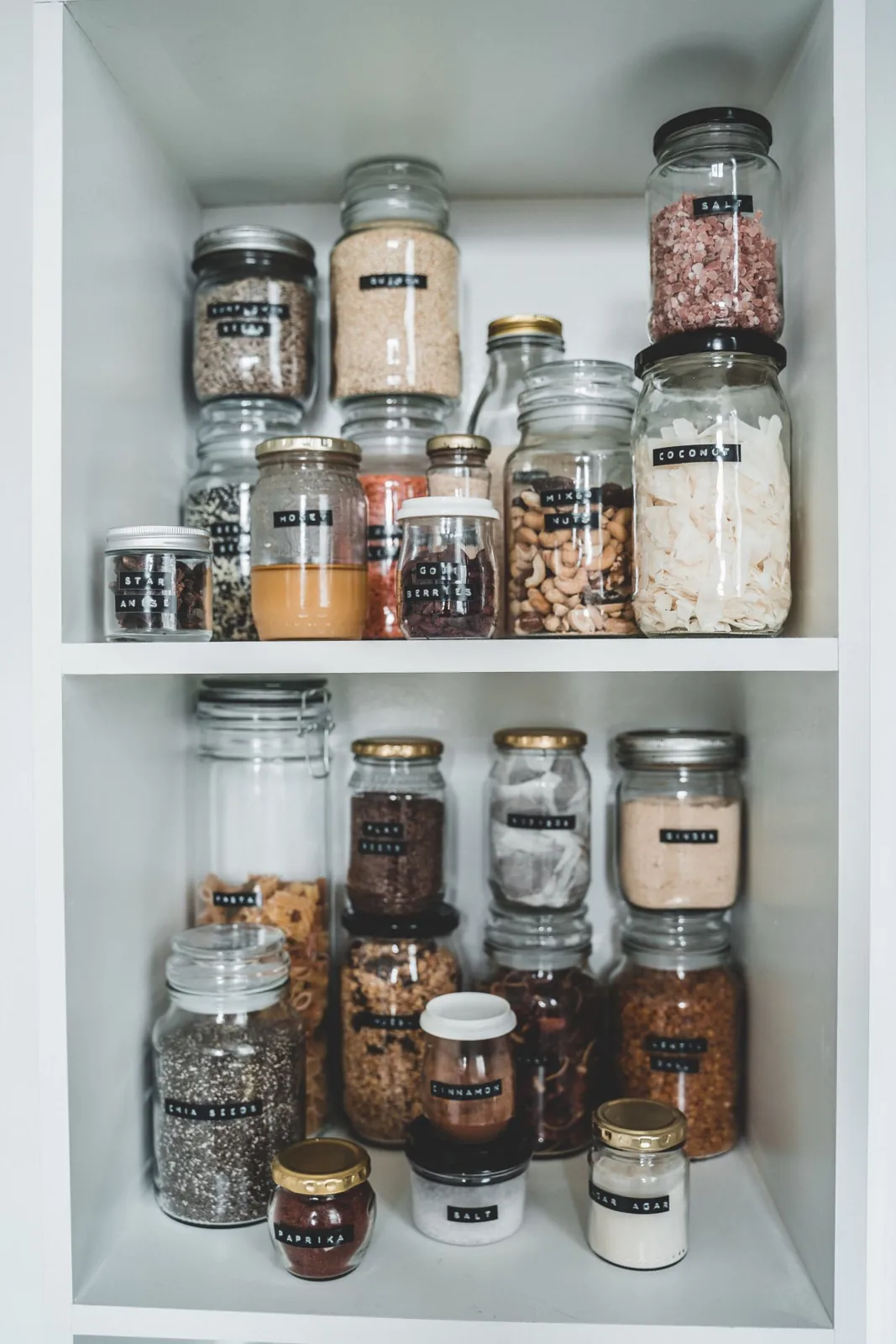 Labelled glass food jars arranged on pantry shelves