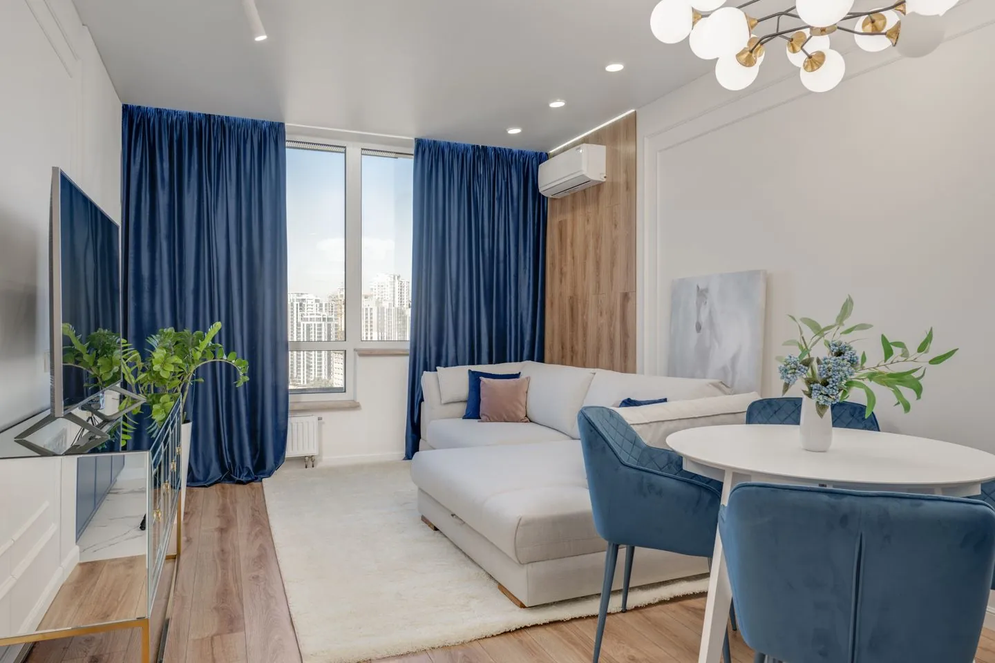 Long living room with pale furniture and blue curtains