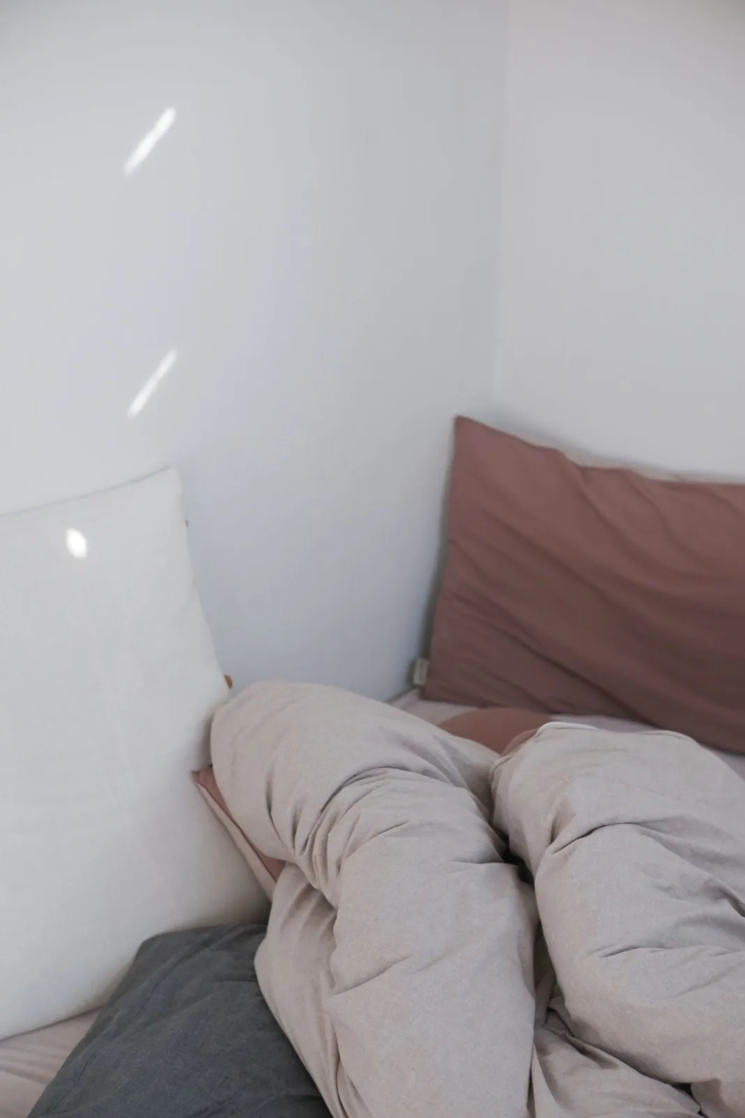 Layered bedding and pillows in muted pink and white