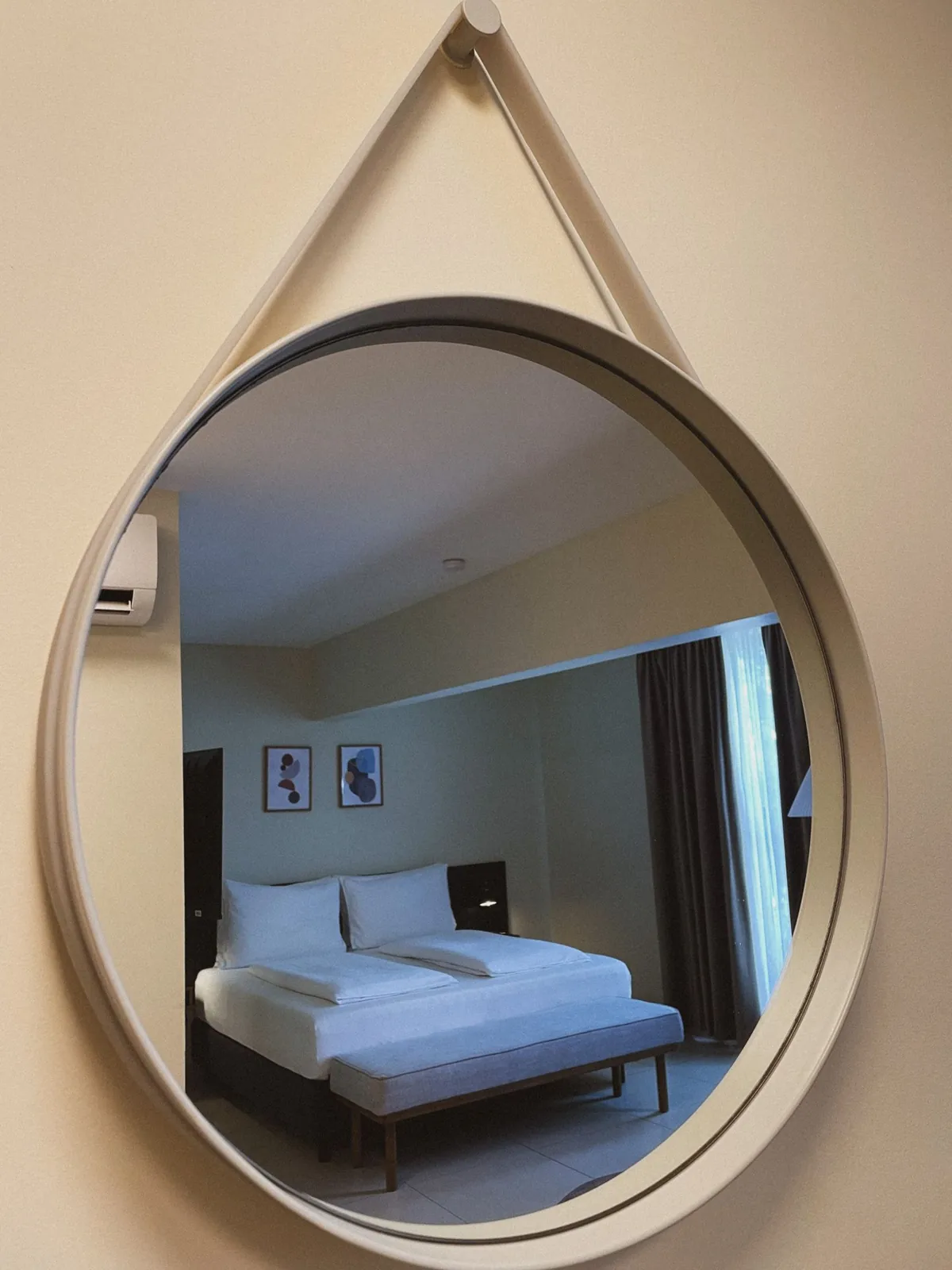 Round mirror reflecting a bedroom interior